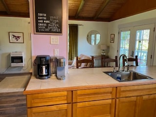 kitchen featuring wooden ceiling, sink, heating unit, lofted ceiling, and tile counters