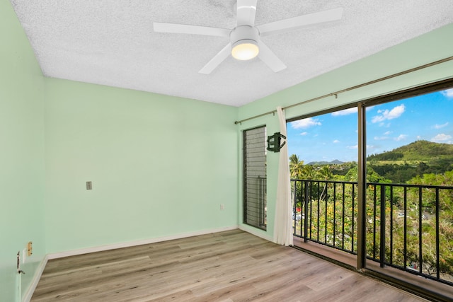 unfurnished room featuring a textured ceiling, light hardwood / wood-style floors, and ceiling fan