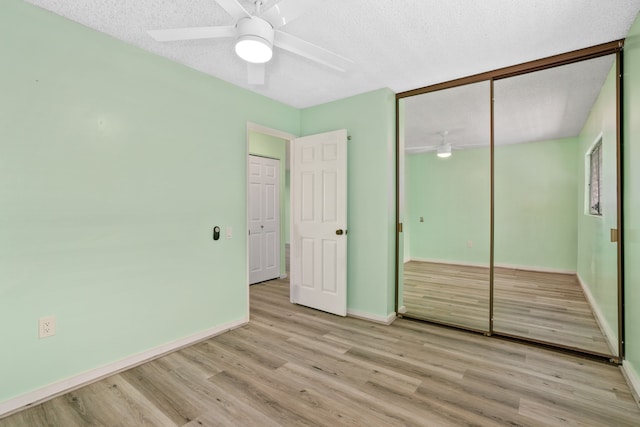 unfurnished bedroom featuring a closet, light wood-type flooring, a textured ceiling, and ceiling fan