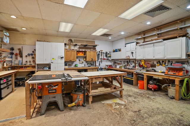 miscellaneous room featuring a workshop area and a drop ceiling