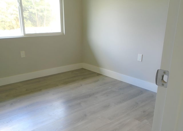 unfurnished room with baseboards and light wood-style flooring