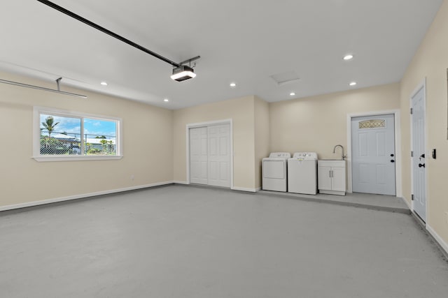 garage with washer and dryer, a garage door opener, and sink