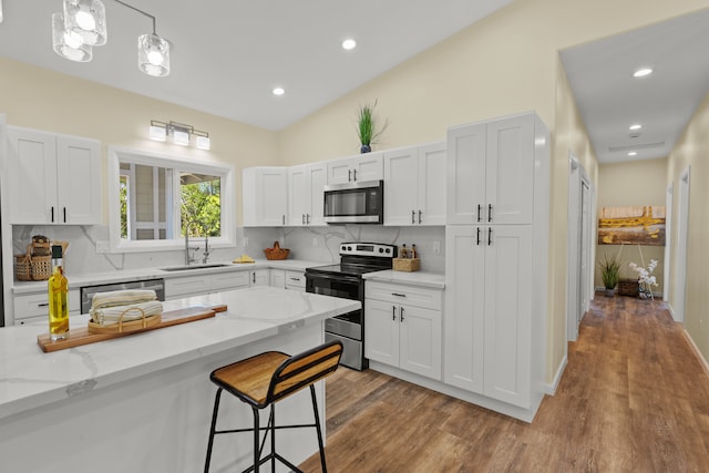 kitchen featuring hardwood / wood-style floors, white cabinetry, hanging light fixtures, and stainless steel appliances