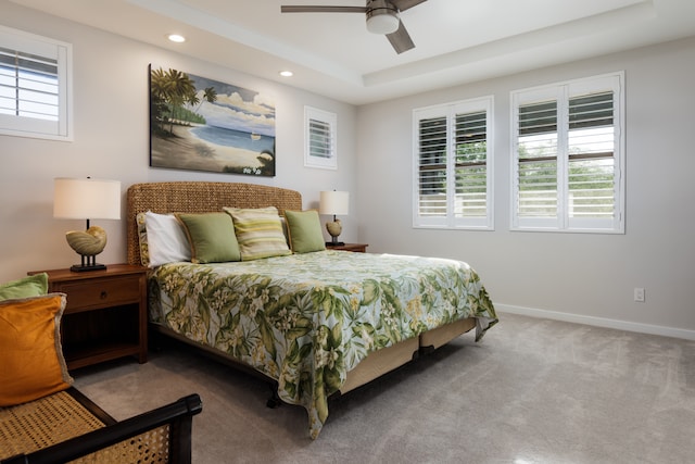 carpeted bedroom with a tray ceiling and ceiling fan