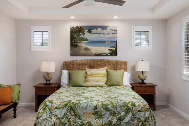 carpeted bedroom with a tray ceiling and ceiling fan