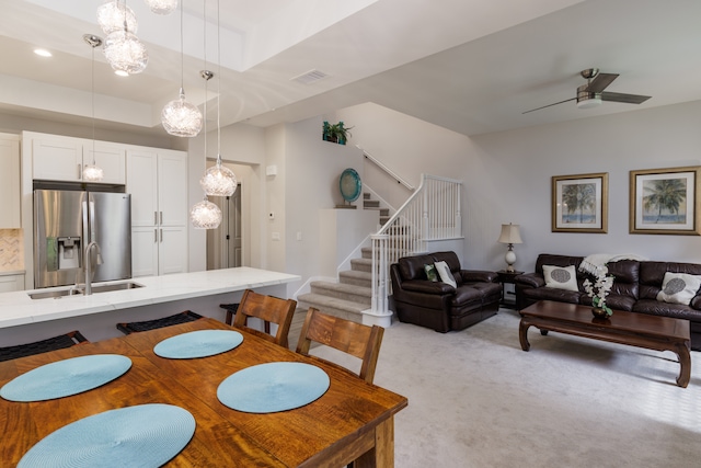 carpeted dining space featuring sink, a tray ceiling, and ceiling fan