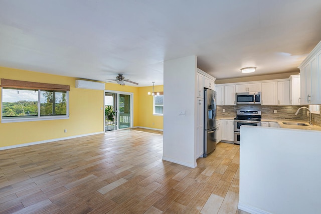 kitchen with appliances with stainless steel finishes, ceiling fan with notable chandelier, sink, light hardwood / wood-style flooring, and white cabinets