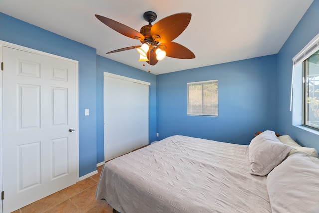 bedroom with multiple windows, light tile patterned floors, and ceiling fan