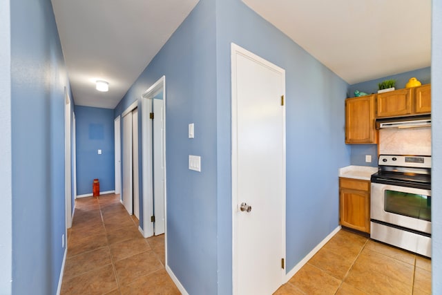 kitchen with stainless steel electric stove and light tile patterned floors