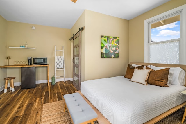 bedroom featuring lofted ceiling, stainless steel refrigerator, dark hardwood / wood-style flooring, and a barn door