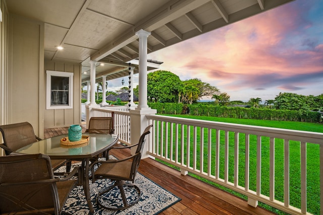 deck at dusk with covered porch and a yard