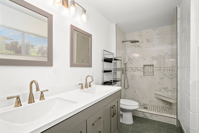 bathroom with vanity, a tile shower, toilet, and tile patterned flooring