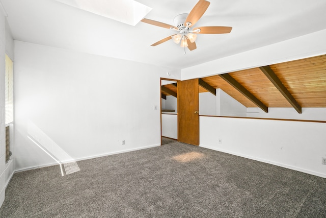 carpeted spare room with vaulted ceiling with skylight, ceiling fan, and wooden ceiling