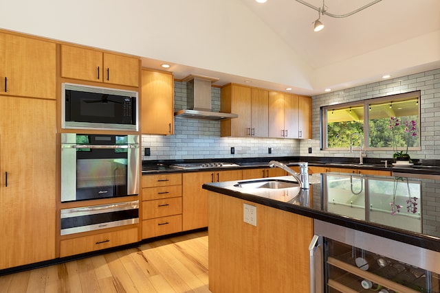 kitchen with light hardwood / wood-style floors, sink, appliances with stainless steel finishes, beverage cooler, and lofted ceiling