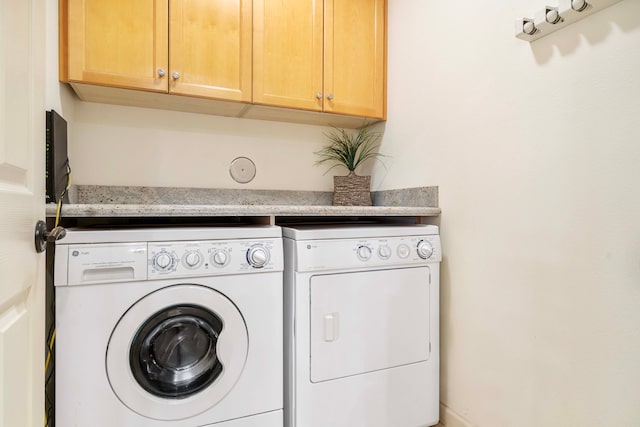 washroom with independent washer and dryer and cabinets