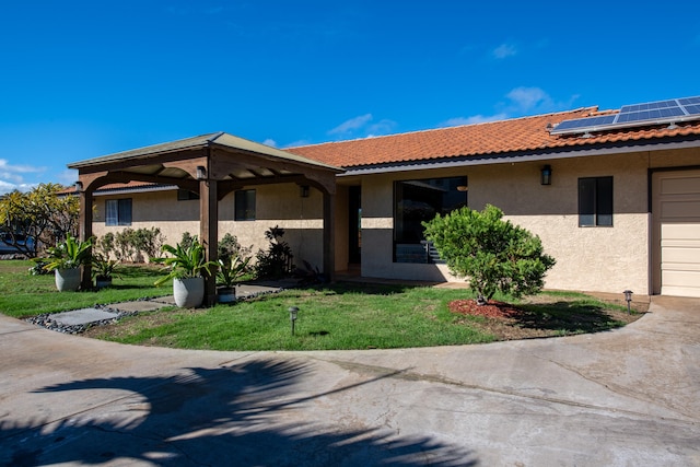 ranch-style home with a garage, a front yard, and solar panels