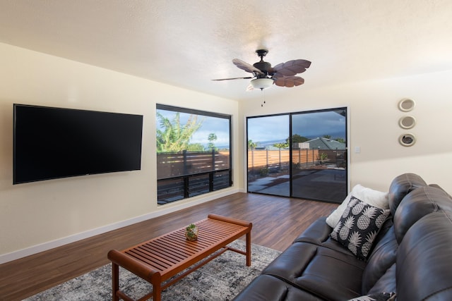 living room featuring ceiling fan and dark wood-type flooring