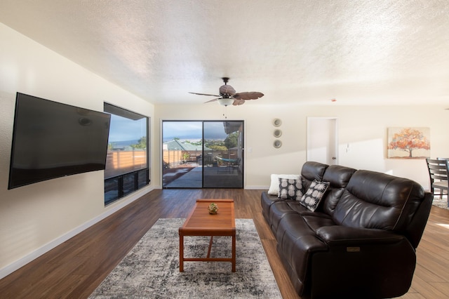 living room featuring a textured ceiling, ceiling fan, and dark wood-type flooring