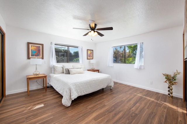 bedroom with multiple windows, ceiling fan, dark hardwood / wood-style flooring, and a textured ceiling