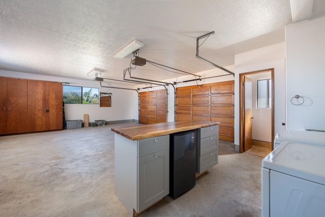 interior space with butcher block countertops, refrigerator, a textured ceiling, washer / dryer, and gray cabinets