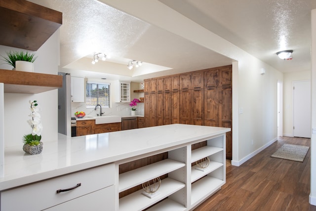 kitchen with sink, a textured ceiling, dark hardwood / wood-style floors, a raised ceiling, and white cabinets