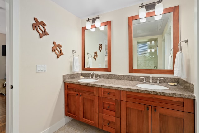 bathroom featuring double vanity, a tile shower, tile patterned flooring, and a sink