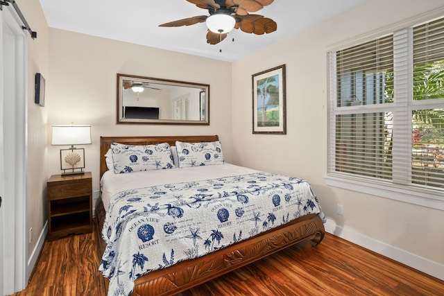 bedroom featuring wood finished floors, ceiling fan, a barn door, and baseboards