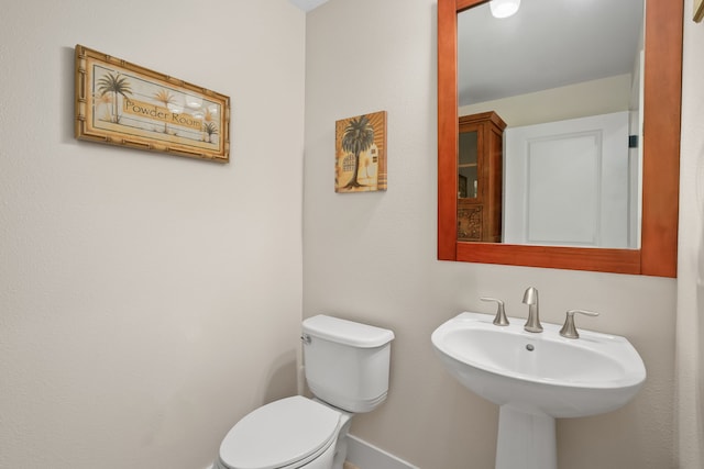 bathroom with toilet, a sink, and baseboards