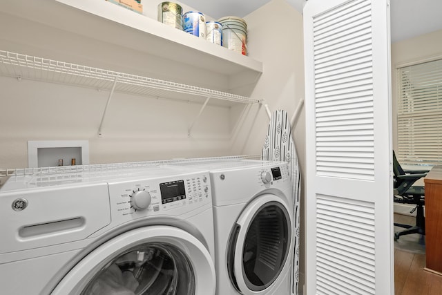 clothes washing area with wood finished floors, laundry area, and washer and clothes dryer