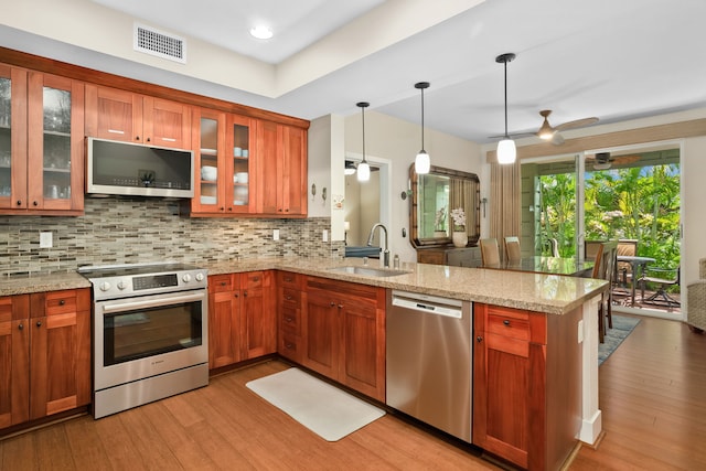 kitchen with a sink, visible vents, stainless steel appliances, light wood-style floors, and a peninsula