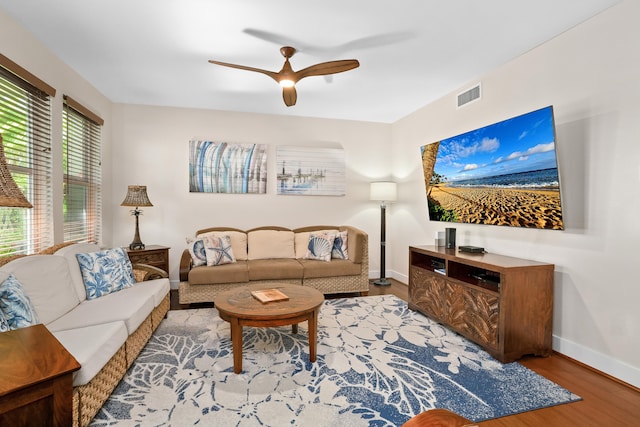 living room with a ceiling fan, visible vents, wood finished floors, and baseboards