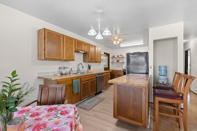 kitchen with light wood-type flooring, dishwasher, black refrigerator, ceiling fan with notable chandelier, and decorative light fixtures