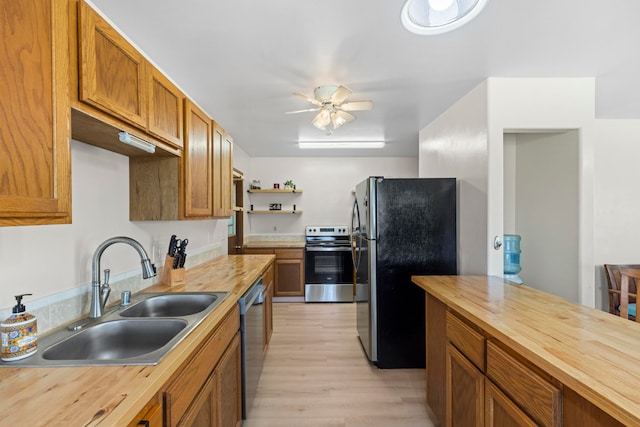 kitchen with butcher block counters, stainless steel appliances, sink, light wood-type flooring, and ceiling fan