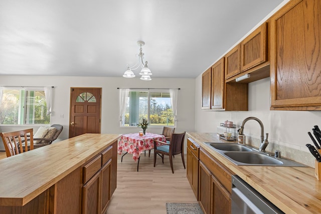 kitchen with wood counters, a healthy amount of sunlight, decorative light fixtures, and light wood-type flooring