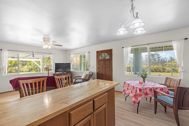 kitchen with light hardwood / wood-style flooring, wood counters, decorative light fixtures, and ceiling fan with notable chandelier