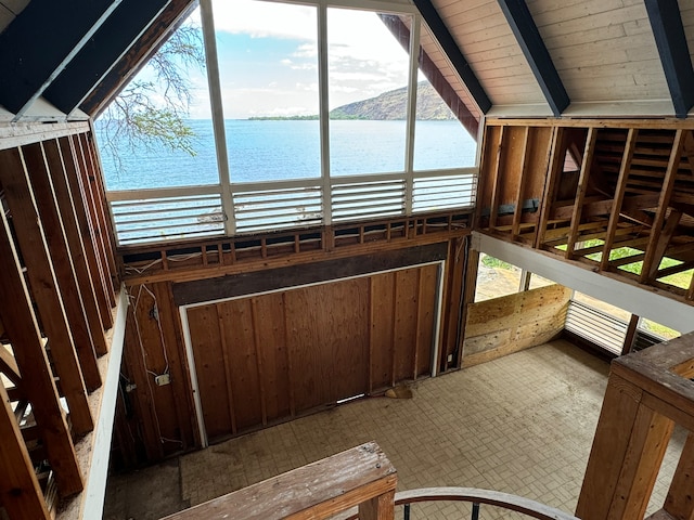 unfurnished sunroom featuring a wealth of natural light, vaulted ceiling with beams, and a water view