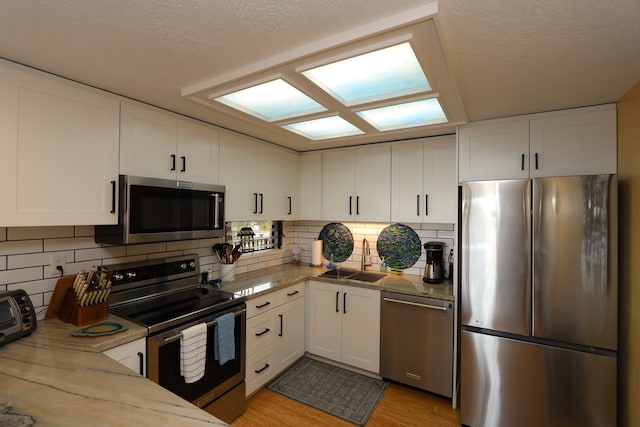 kitchen featuring light hardwood / wood-style floors, white cabinetry, stainless steel appliances, and sink