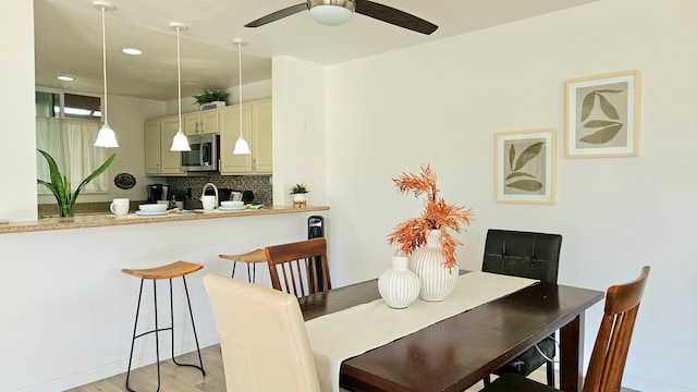 dining space with ceiling fan and light hardwood / wood-style flooring