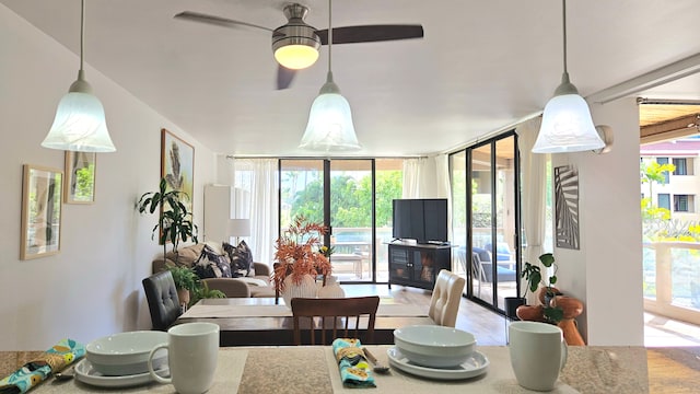 dining space featuring ceiling fan, plenty of natural light, and a wall of windows