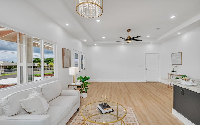 living room featuring ceiling fan with notable chandelier and light wood-type flooring