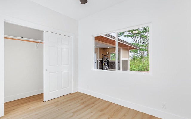 unfurnished bedroom featuring ceiling fan, a closet, and wood-type flooring