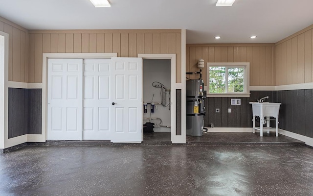 garage featuring water heater, sink, and wood walls