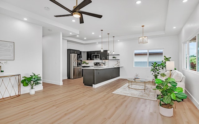 kitchen with decorative light fixtures, ceiling fan, appliances with stainless steel finishes, and light hardwood / wood-style flooring