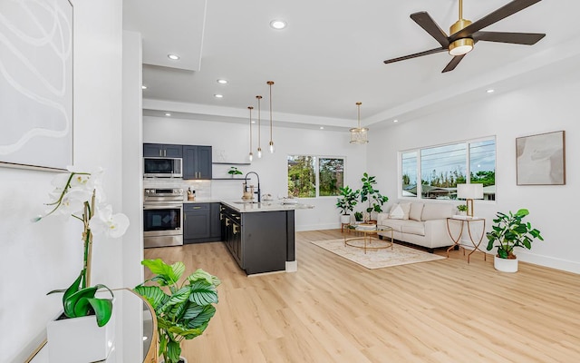 kitchen with stainless steel appliances, ceiling fan, sink, light hardwood / wood-style flooring, and hanging light fixtures