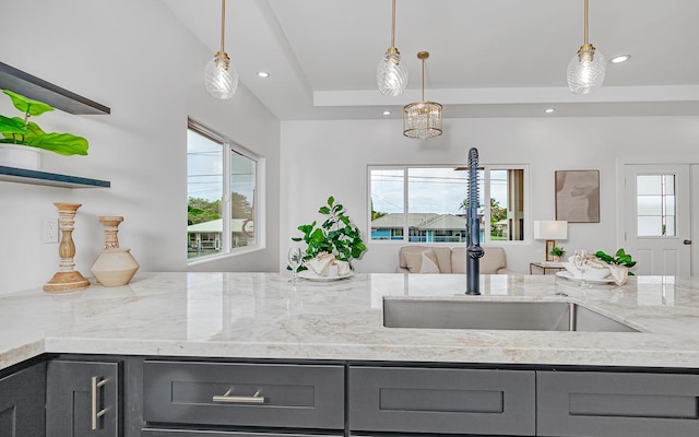 kitchen featuring pendant lighting, light stone counters, and a wealth of natural light