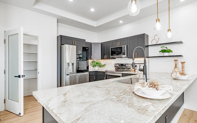 kitchen with sink, tasteful backsplash, light hardwood / wood-style floors, kitchen peninsula, and stainless steel appliances