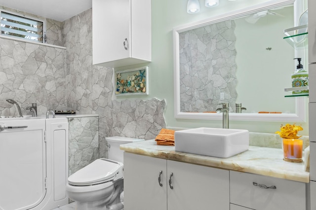 bathroom featuring vanity, toilet, and tile walls