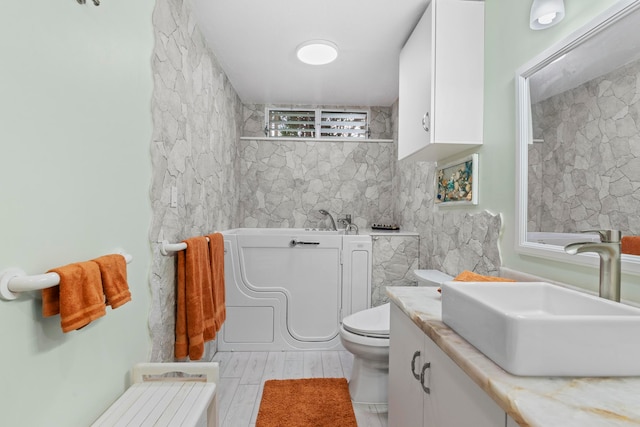 bathroom with a tub, hardwood / wood-style floors, vanity, and toilet