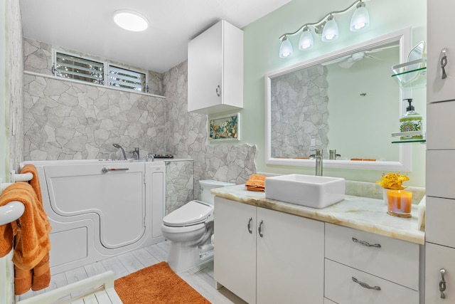 bathroom featuring vanity, toilet, and tile walls