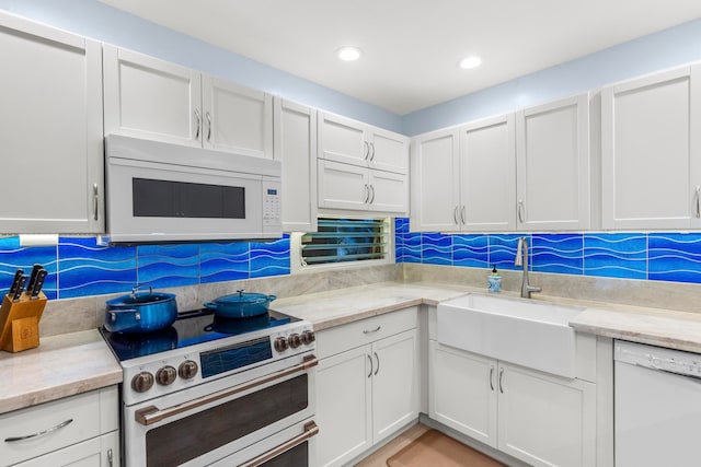 kitchen featuring decorative backsplash, white cabinetry, and white appliances